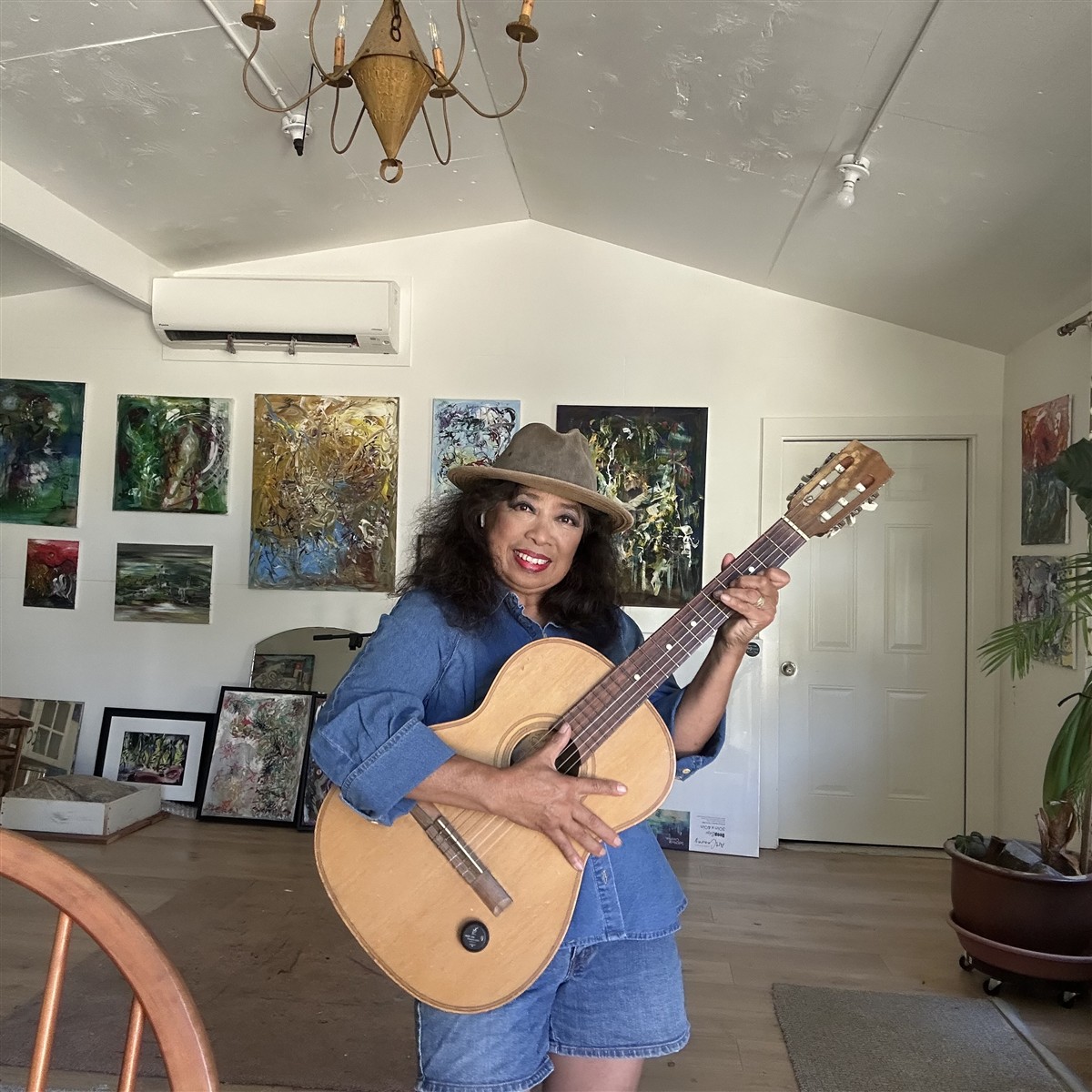 Michelle playing guitar in a room filled with artwork