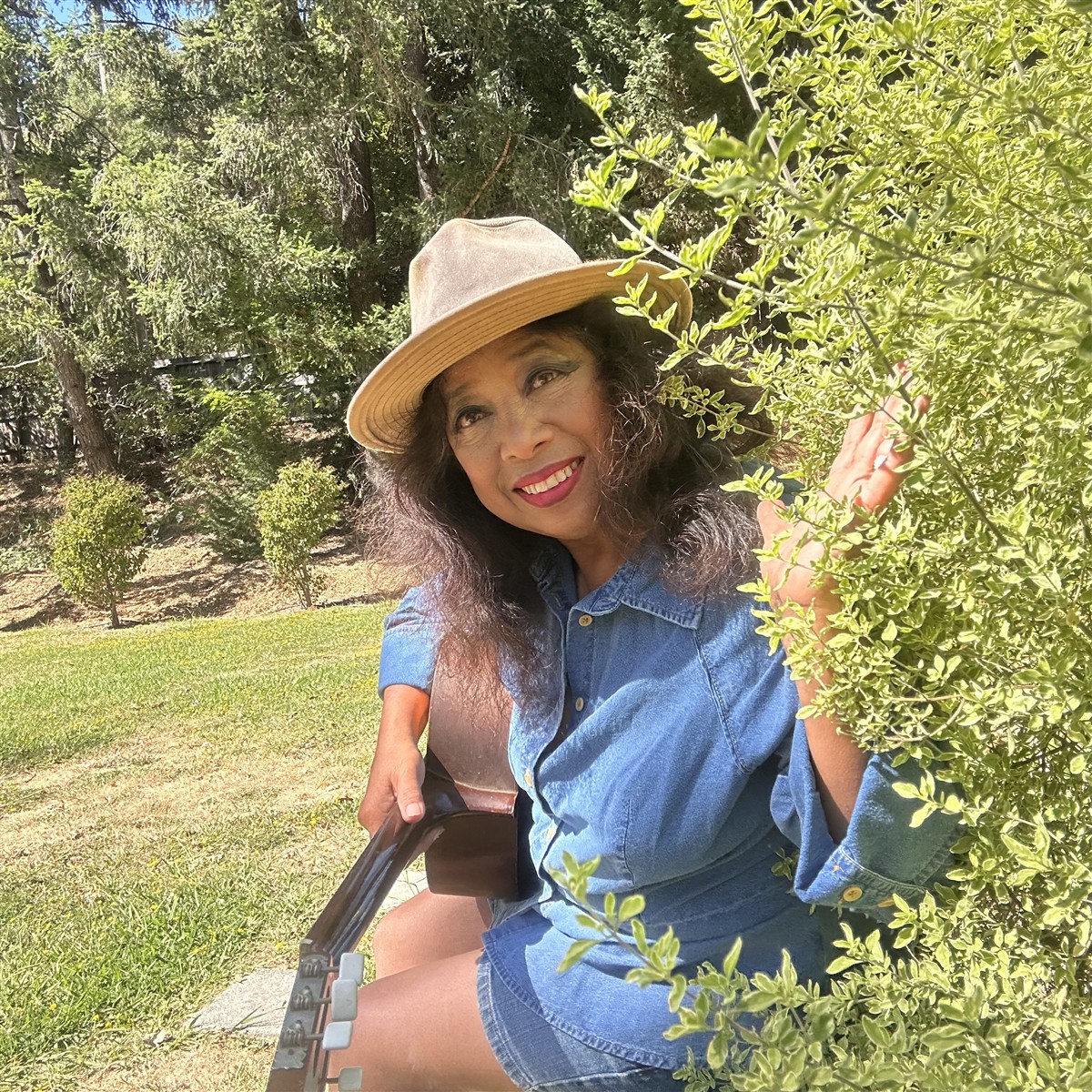 Michelle sitting beside lush greenery in a sunlit garden